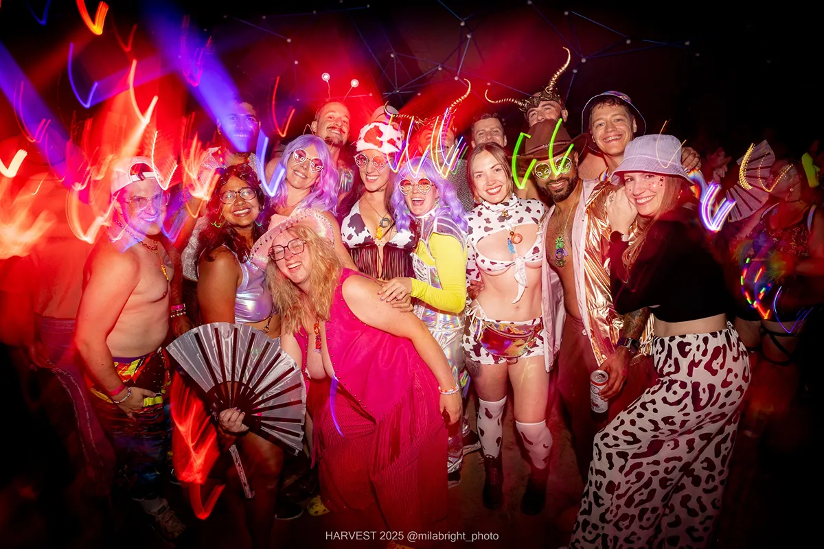 Costumed group at Crystal Six event, vibrant lights, diverse outfits