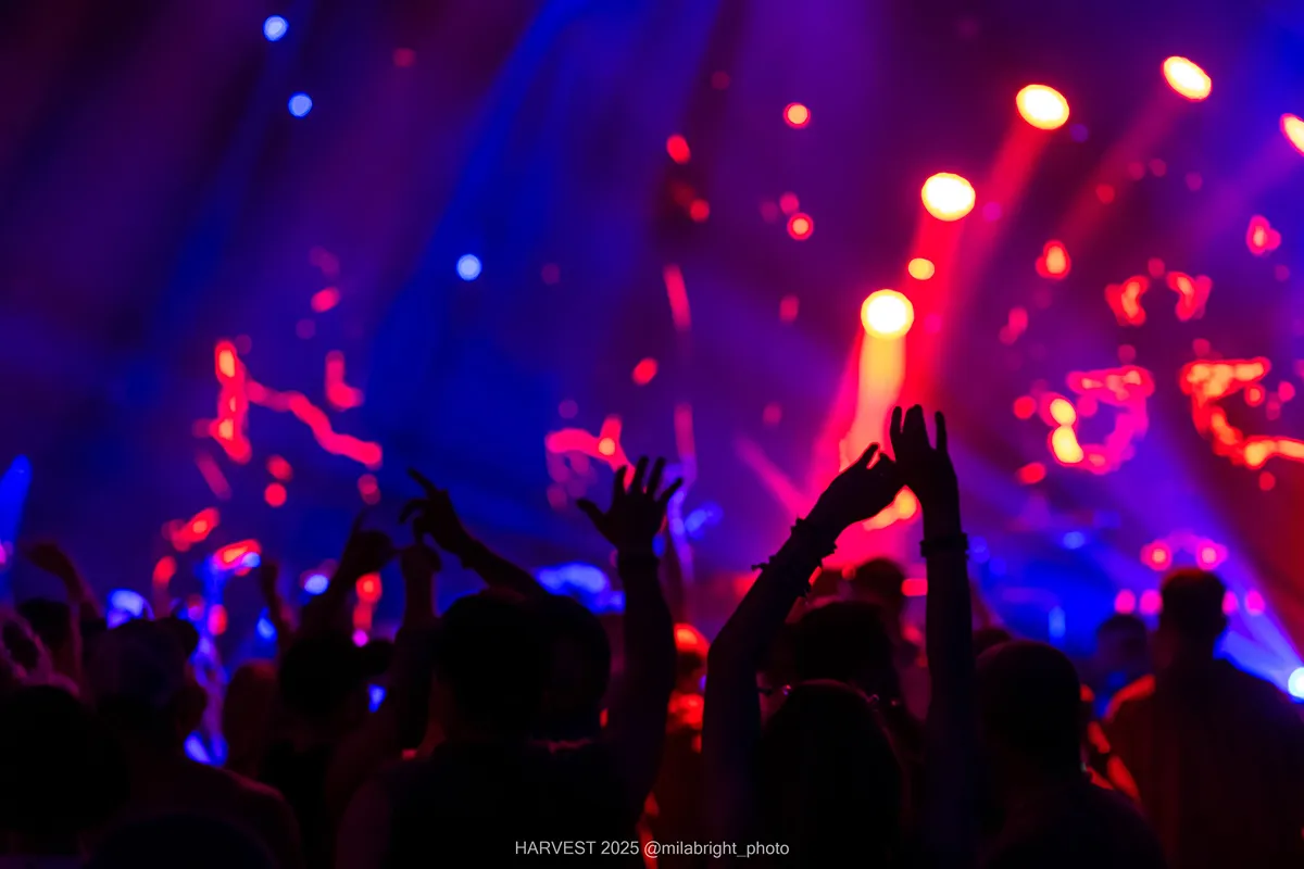 Crowd with hands up at a vibrant Crystal Six concert with red and blue lights