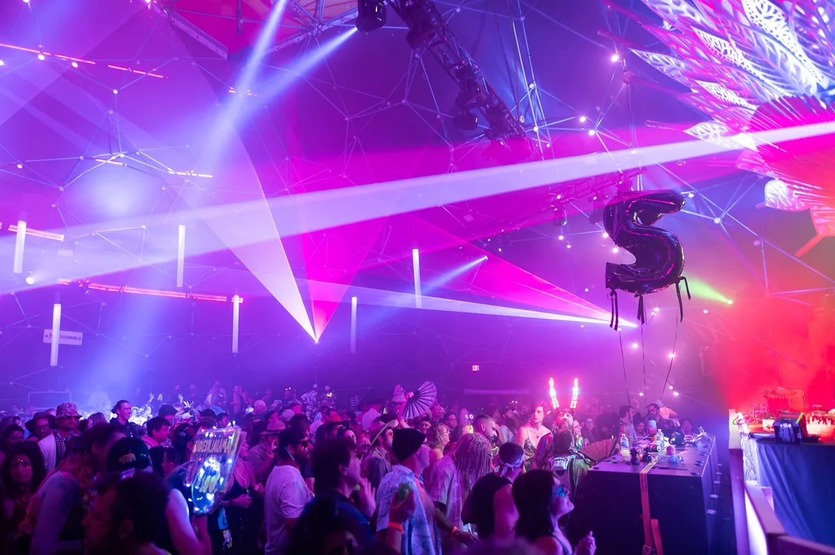Crystal Six: Energetic crowd at a vibrant, neon-lit music festival with a giant "6" balloon.