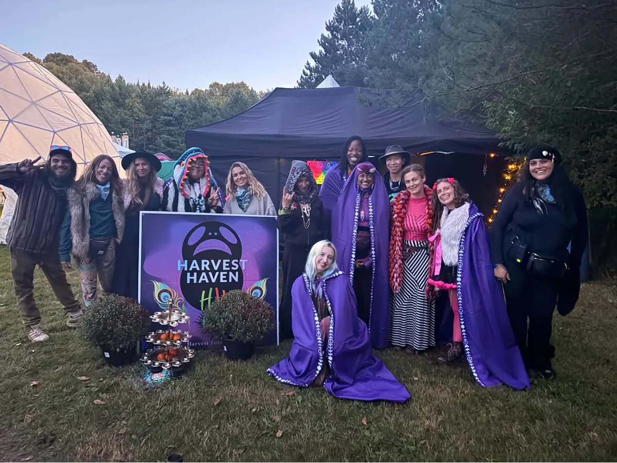 Harvest Haven group photo with festival-goers in purple robes and a geodesic dome