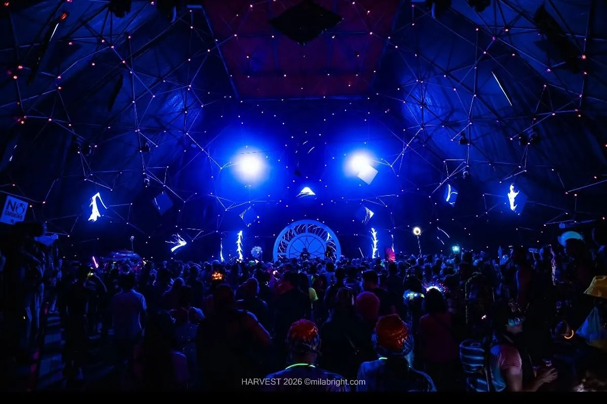 Crowd dancing under a geometric dome stage with blue lights at a music festival