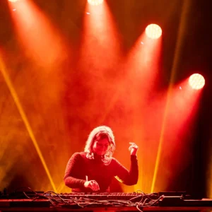 beth-lydi-handup-tallandvibin DJ performing on stage with red and yellow stage lights