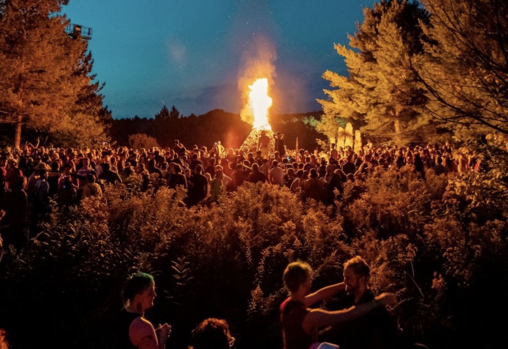 A large bonfire surrounded by crowd