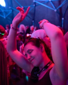 dancer-side-profile-tallandvibin Woman dancing with arms raised at a vibrant, neon-lit event.