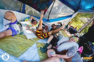 kets-plounge-by-zac-mac Festival-goers in a tent, some wearing colorful outfits, enjoying themselves.