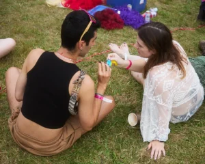 Couple in festival attire sitting on grass, sharing a moment