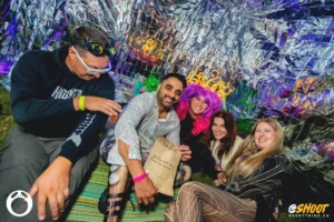 tinsel-tent-by-zac-mac Group of friends enjoying a festival, one holding a sign with text